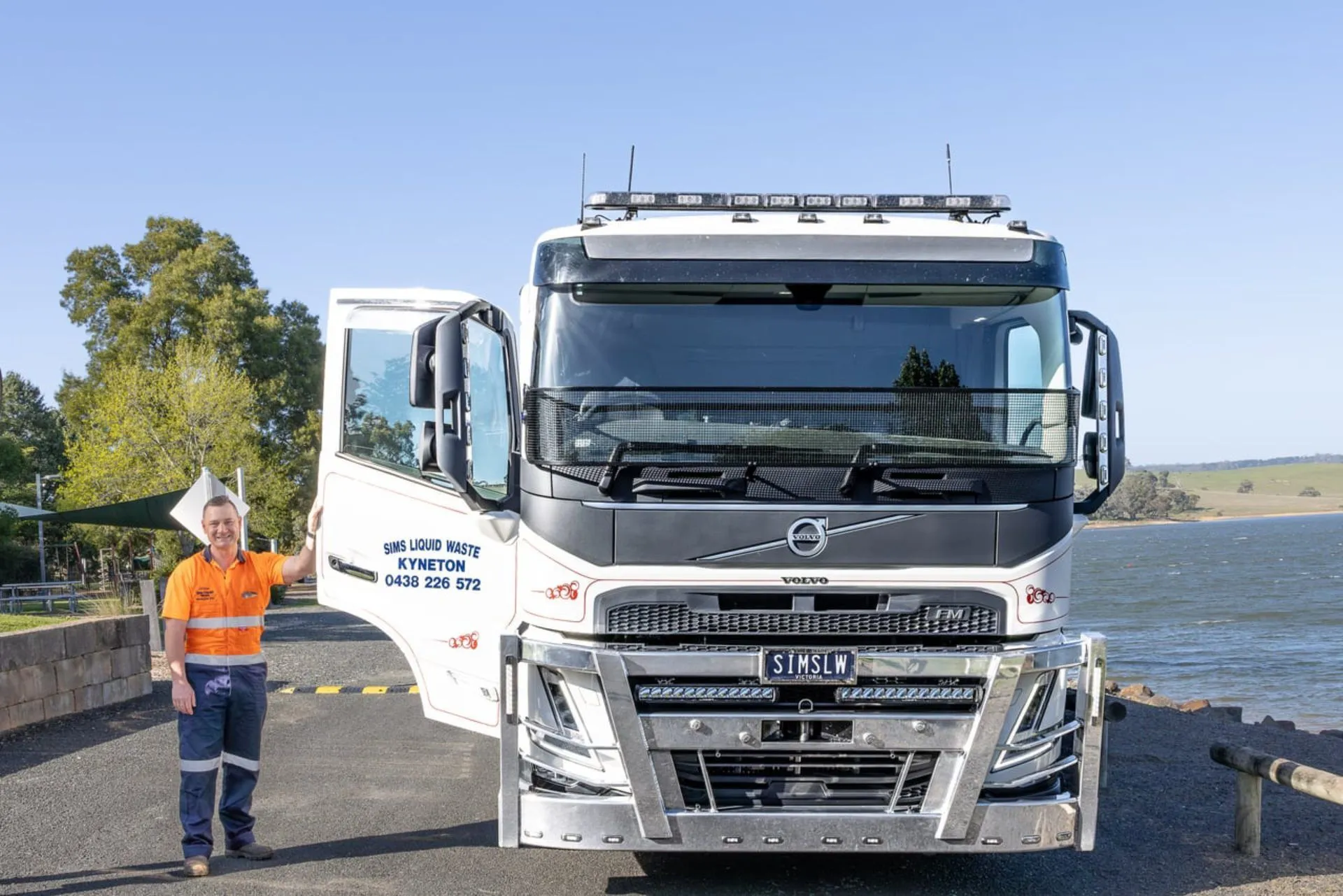 Sims Liquid Waste driver in hi-vis beside the cab of a white tanker truck